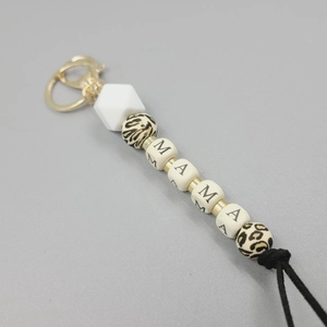 Macro detail of MAMA silicone bead keychain with leopard print accents and gold clasp