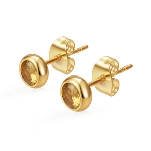 Gros plan de boucles d'oreilles rondes plaquées or 18K avec zircone jaune sertie clos