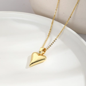 Elegant gold heart pendant necklace with zircon inlay on minimalist white ceramic tray