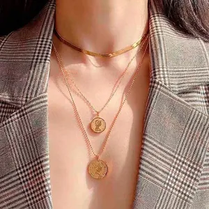 Minimalist gold snake bone chain necklace layered with vintage portrait coin pendants