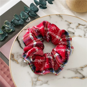 Close-up of red plaid Christmas scrunchie with snowflake pattern on marble tray