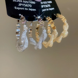 Macro view of gold and silver plated woven hoop earrings with 925 silver needles
