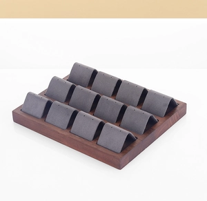 Macro detail of walnut wood base with 12 grey velvet earring display slots