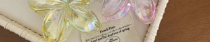 Close-up of iridescent plumeria flower hair claws in yellow and pink on a woven tray