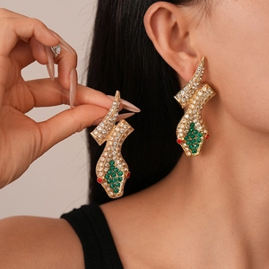Exaggerated golden snake drop earrings with sparkling rhinestones and green crystal accents