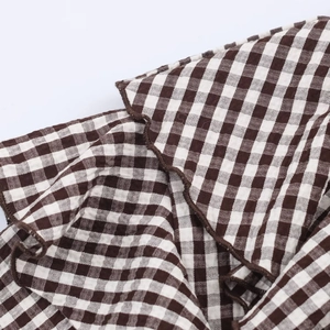 Detail of ruffle trim and brown gingham pattern on woven fabric for women blouse
