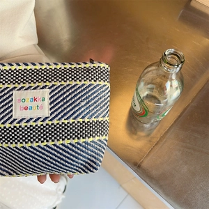Detail of colorful woven stripes on a large capacity toiletry bag with zipper
