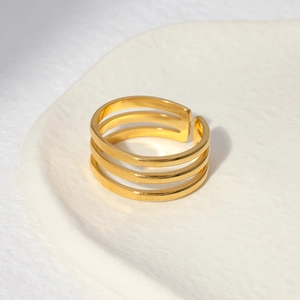 Detailed view of a triple-layered golden minimalist open ring on a ceramic tray