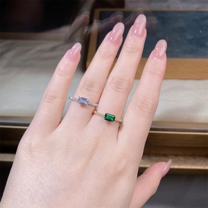 Close-up of stacked V-shaped silver and gold rings with emerald and lavender crystals