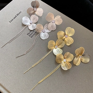 Macro shot of silver and gold floral tassel earrings with zircon on a textured book
