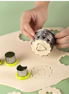 Detail of hand using a stainless steel flower mold to cut heart shapes in dough