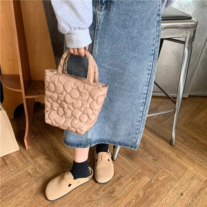 Detailed close-up of the floral quilted pattern and fabric texture of the beige handbag