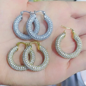 Close-up of sparkling 18K gold and silver hoop earrings with full pavé cubic zirconia