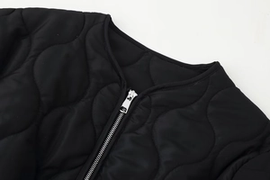 Détail du col rond et du zip argenté sur la veste matelassée noire avec motif de gourde