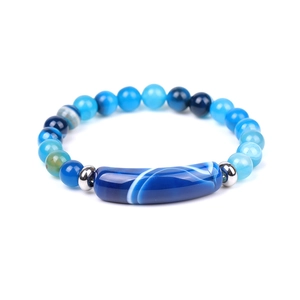 Macro detail of blue agate bracelet featuring round beads and long stone charm