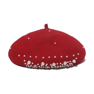 Detailed view of red wool beret adorned with elegant pearls and sparkling rhinestones