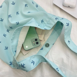Detailed interior of blue swallow print canvas tote with magnetic clasp and daily items