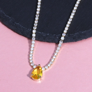 Detail of gold necklace with yellow pear-cut gemstone and paved zircon accents