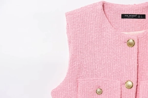 Detail of pink tweed fabric texture with gold metallic button and brand size label