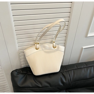 Detailed view of cream pleated handbag with vertical texture and golden rings