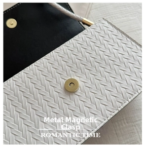Detail of white woven PU leather bag featuring a gold magnetic snap button closure
