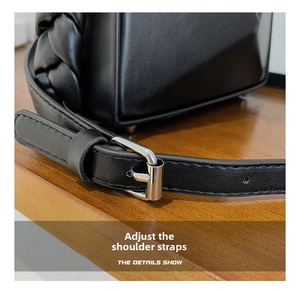 Detailed macro view of adjustable silver buckle and stitching on black leather handbag