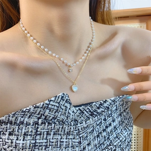 Close-up of double layer pearl necklace with heart pendant and zircon stone on neck