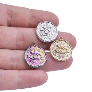 Devil's Eye stainless steel pendants in silver, gold, and rainbow finishes held in hand
