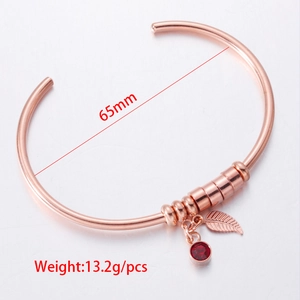 Rose gold stainless steel bangle featuring a leaf charm and red birthstone pendant