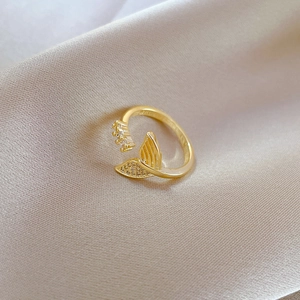 Close-up of golden fishtail open ring with shimmering zircons on silk fabric