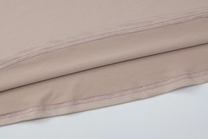 Gros plan sur l'ourlet à double aiguille de la robe plissée française en rose Morandi