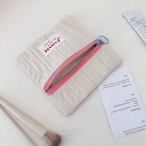 Detail of a pleated makeup bag featuring a pink and blue zipper with a round blue puller
