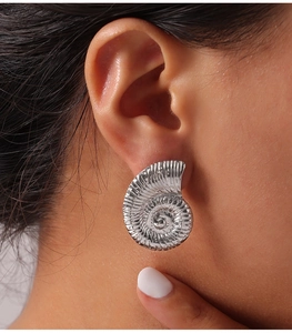 Detailed macro view of silver titanium steel earrings with spiral shell texture on ear