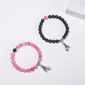Detail of magnetic handshake pendants on pink and black natural stone beaded bracelets
