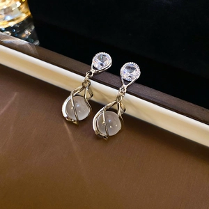 Détail de boucles d'oreilles argentées avec pierre œil de chat et zircons étincelants