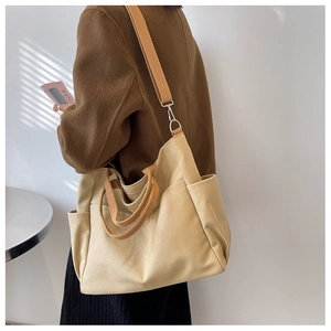 Detail of canvas tote bag with side pocket and long shoulder strap in beige