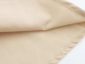 Gros plan du tissu beige de la robe montrant les détails de broderie et la texture