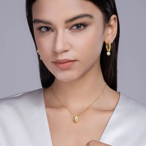 Close-up of gold pear-shaped moissanite necklace and matching earrings on model