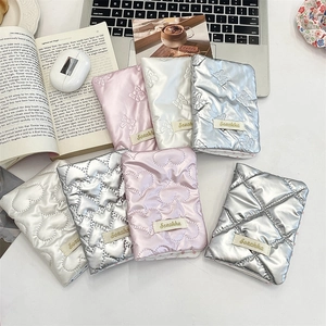 Detailed view of quilted bow passport holders in metallic pink, silver, and white tones