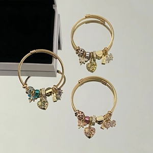 Detailed close-up of woven gold charm bracelets with crystal hearts and enamel beads
