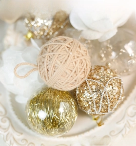 Detailed view of cream yarn balls and gold glitter ornaments in a decorative tray
