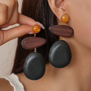 Close-up of model wearing retro resin and wood teardrop earrings in amber and black