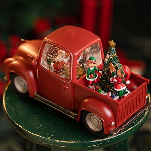 Boîte à musique camion rouge de Noël avec Père Noël, elfes et sapin sur un tabouret