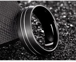 Macro shot of black tungsten ring with silver inlays and brushed metallic texture