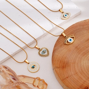 Gold-plated Evil Eye necklace collection with white enamel charms on stone and wood base