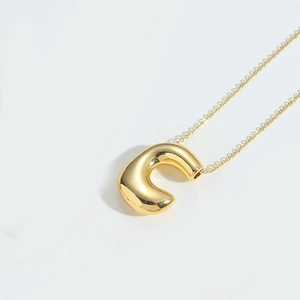 Macro shot of polished gold balloon-style letter pendant on a sleek metal necklace