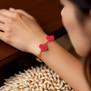 Gros plan d'un bracelet en or 18 carats avec des cœurs en marbre rouge sur un poignet