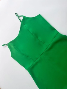 Detail of lime green satin strap dress featuring structured seams and silky texture