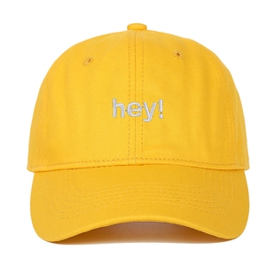 Détail de la casquette de baseball en coton jaune avec broderie 'hey!' et bord surpiqué