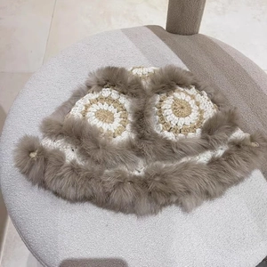 Detail of hand-crocheted patterned winter hat with thick brown faux fur trim